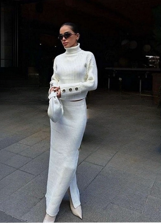 Side profile of women’s white knitted set with slit skirt and turtleneck.