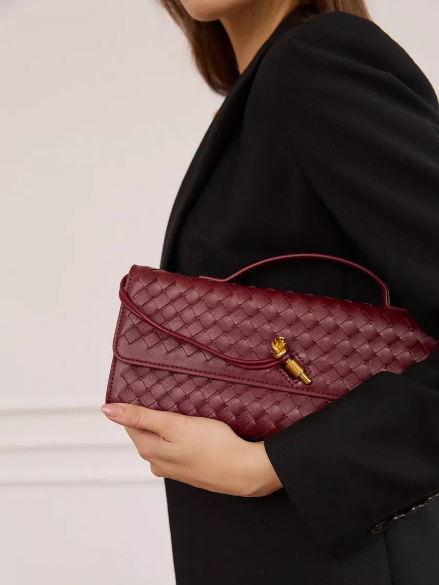 Burgundy woven leather handbag displayed on a surface.