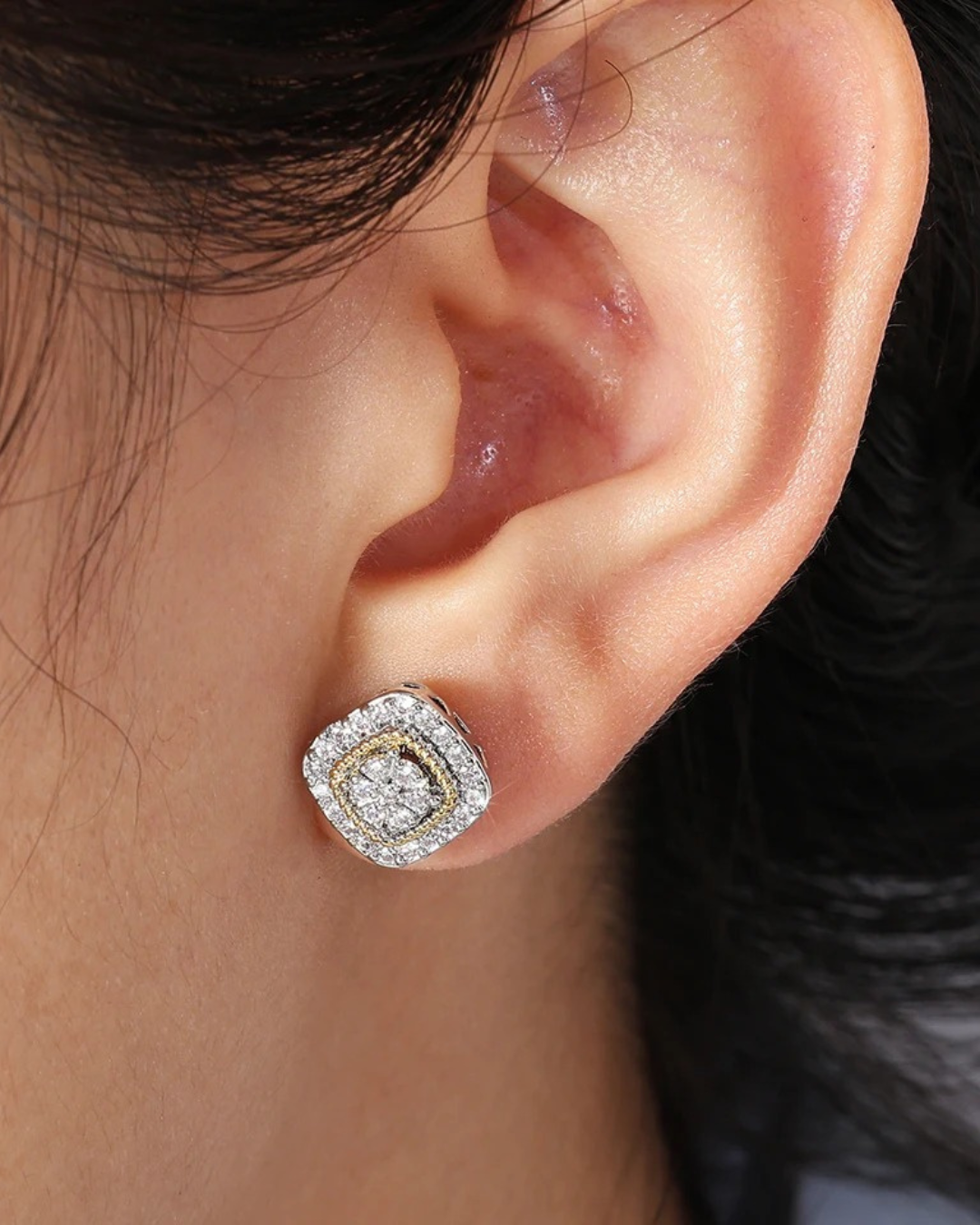 Close-up detailed view of women's zircon earrings with gold and silver cube design